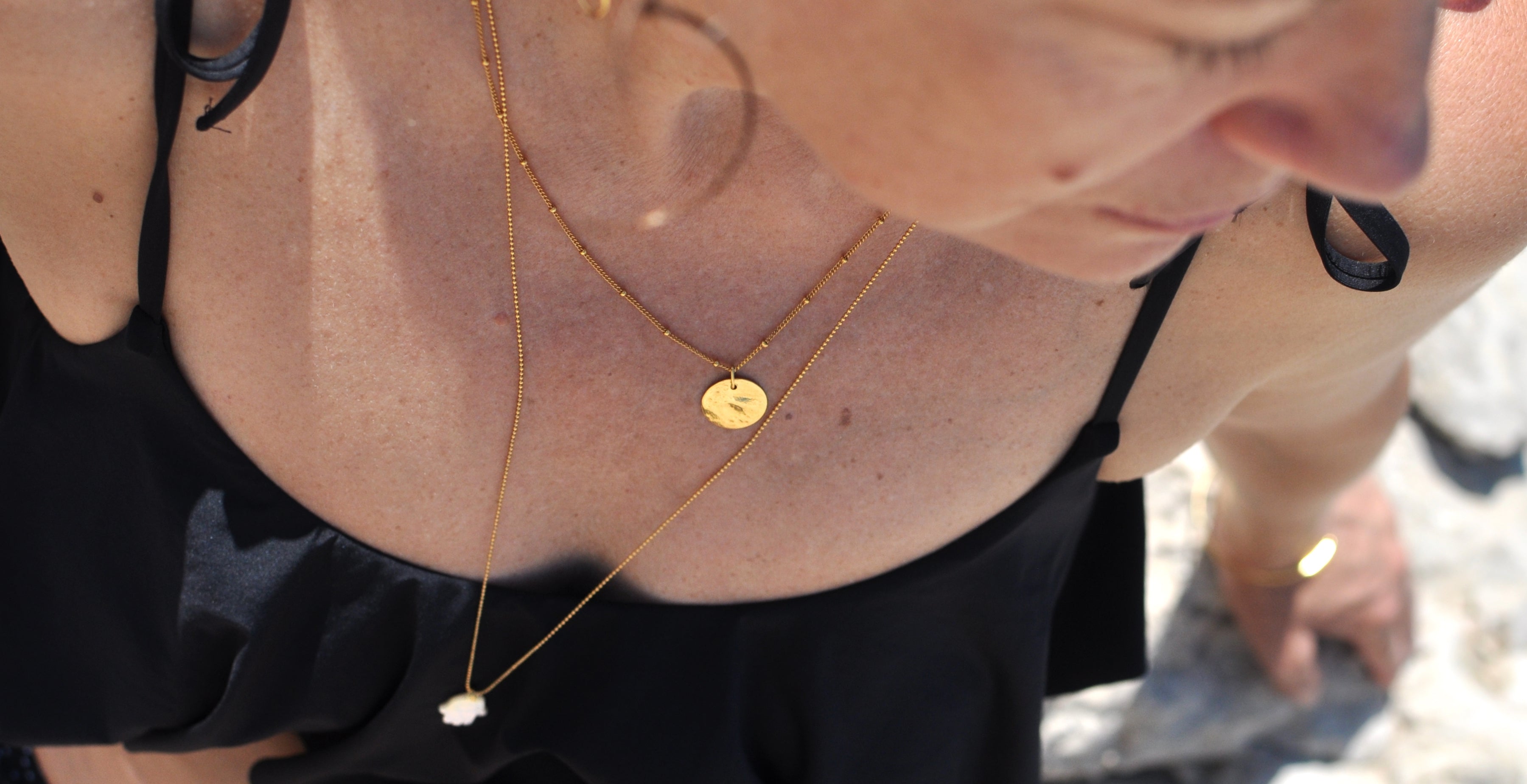 Superposition de colliers avec chaîne gourmette boule, médaille martelée et sautoir avec main de fatma en nacre