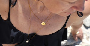 Superposition de colliers avec chaîne gourmette boule, médaille martelée et sautoir avec main de fatma en nacre